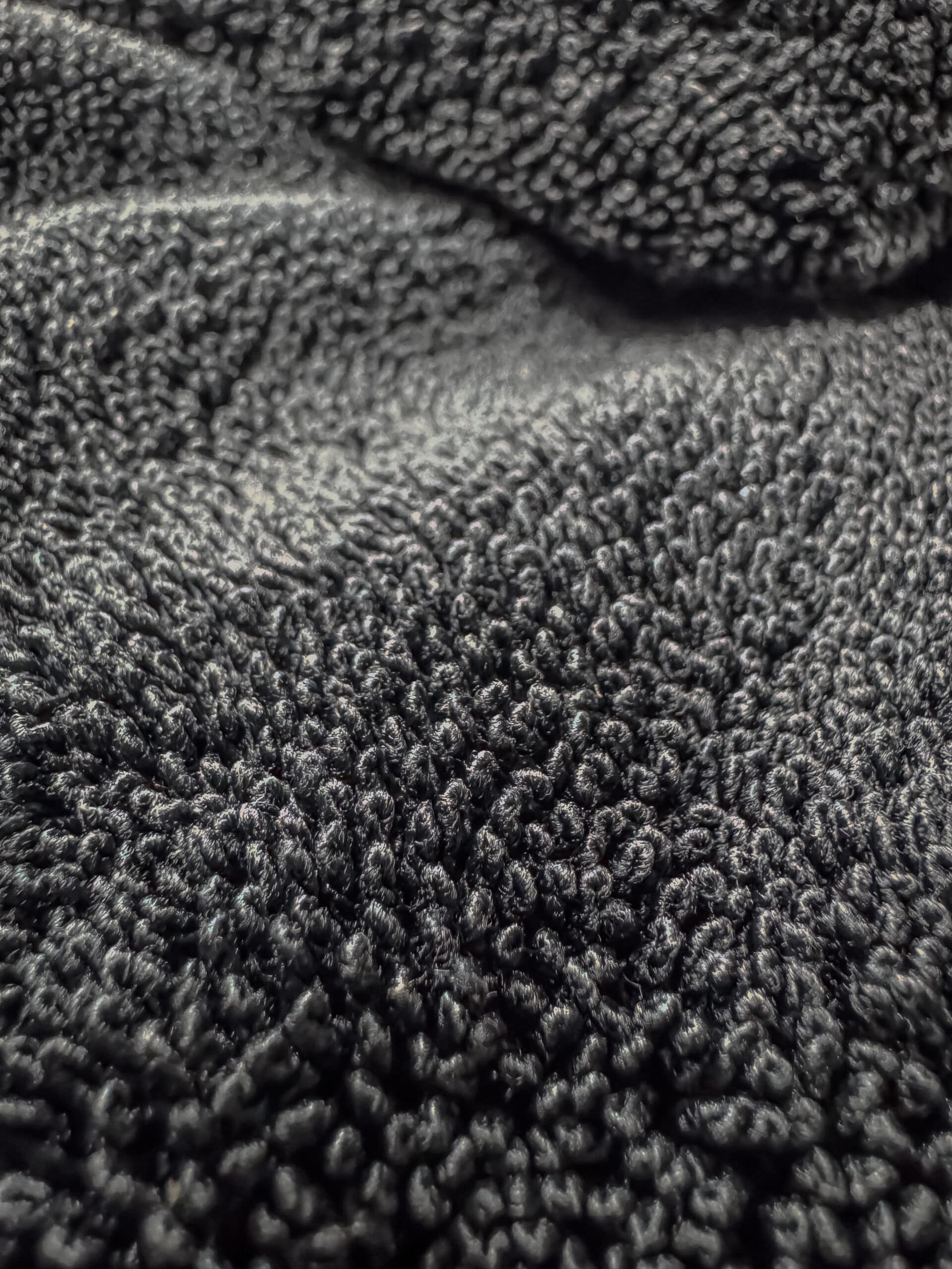 Close-up of HydroLoop twisted loop microfiber car drying towel absorbing water streak-free on a vehicle hood.